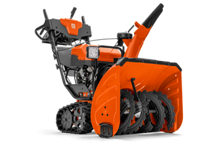 Side view of a Husqvarna snow blower with visible auger and controls.
